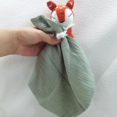 Doudou pour bébé au crochet renard avec lange vert tenu par une main