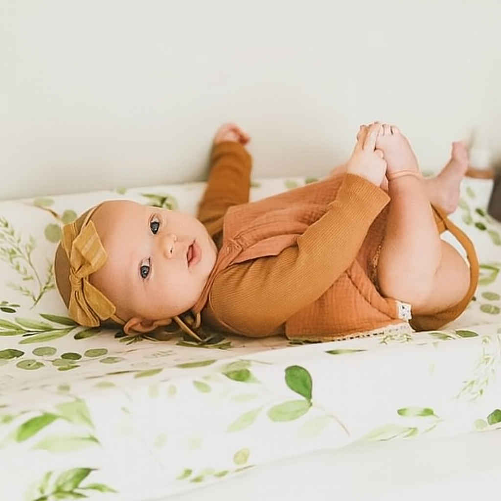 Bébé allongé sur une housse matelas à langer imperméable LeafyCare™, motif feuillage doux et confortable.