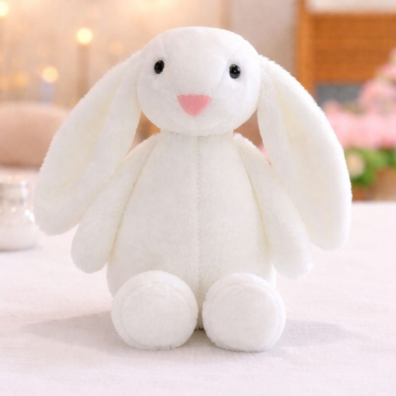 Peluche lapin pour bébé blanche aux longues oreilles posée sur une surface douce