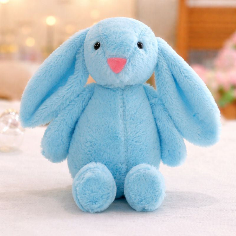 Peluche lapin pour bébé bleu ciel aux longues oreilles posée sur une surface douce