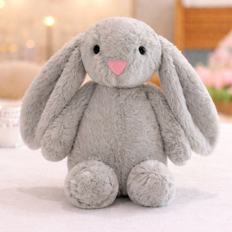Peluche lapin pour bébé gris aux longues oreilles posée sur une surface douce