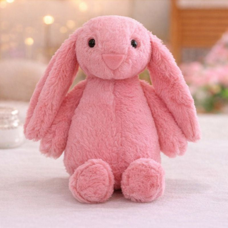 eluche lapin pour bébé rose aux longues oreilles posée sur une surface douce